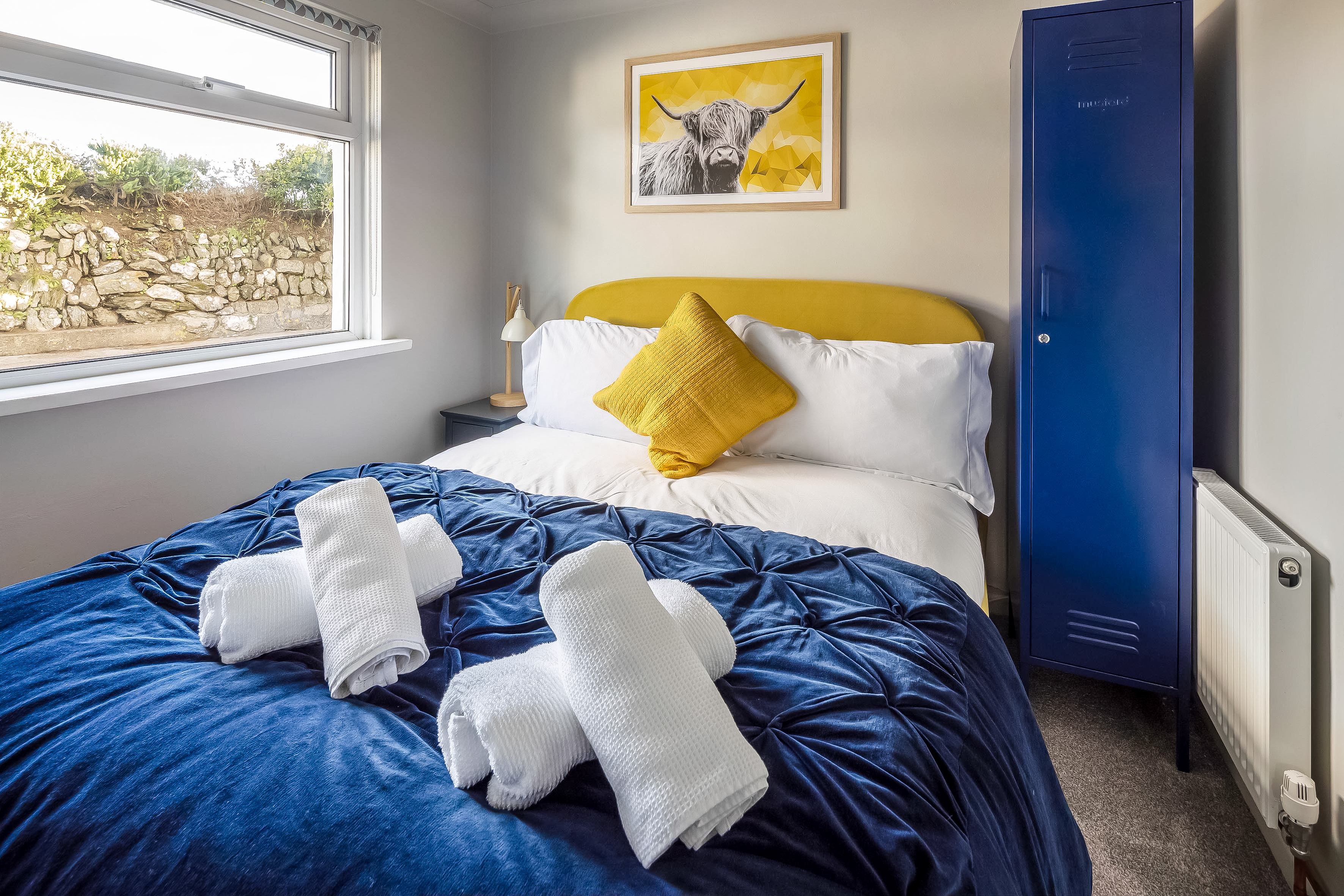 Cosy bedroom with navy bedding, mustard accents and highland cow print